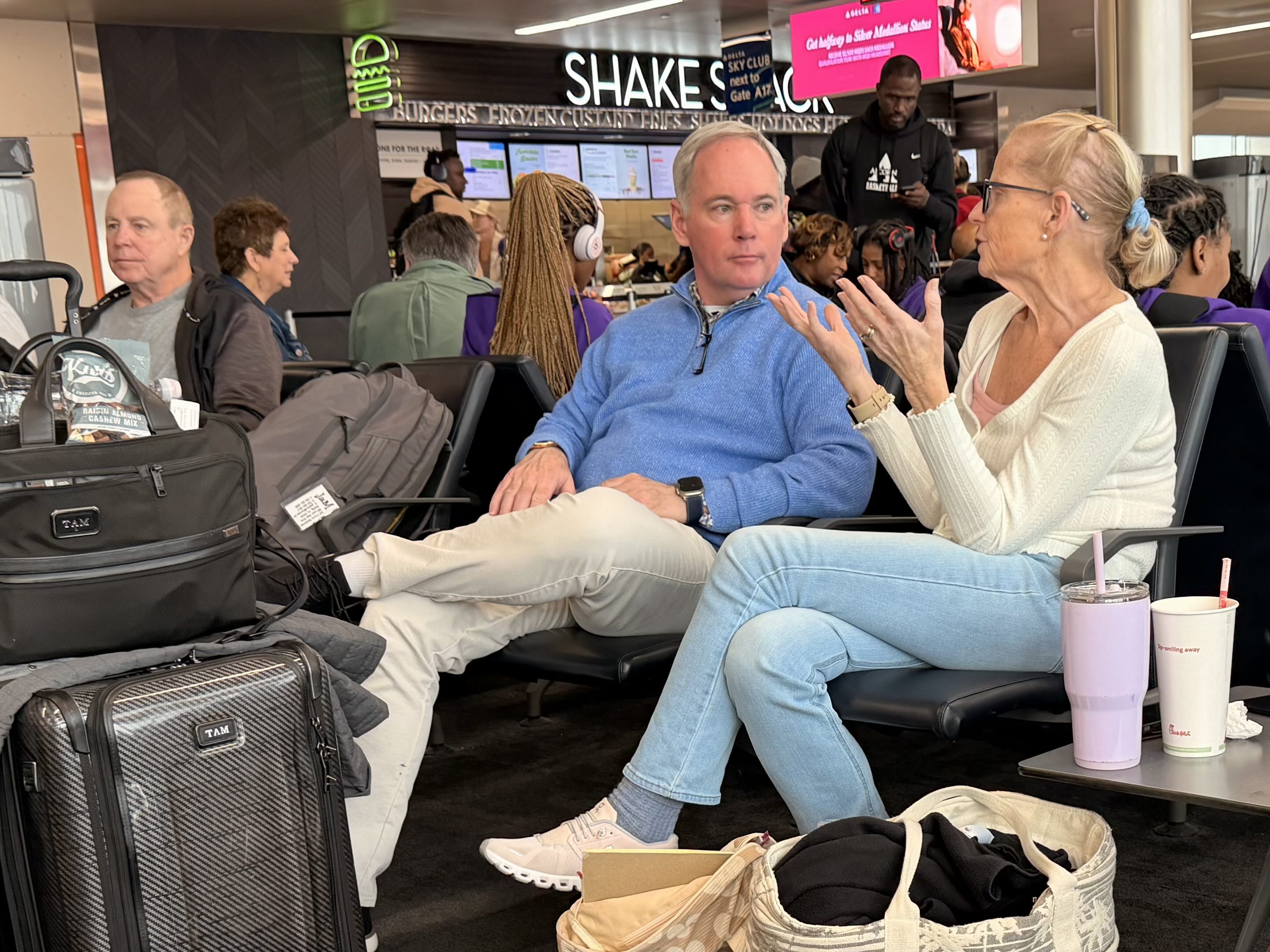 A man and a woman having a conversation at a crowded airport gate